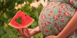 watermelon slice in the hand of a pregnant woman